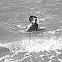 child, boy, water, ocean, waves, beach, playing, splashing, smiling, fun, people, sea, shore, summer, outdoor, black_and_white, happy, young, vacation, nature