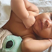 Jamar is registered to the contest to win money with this photo: baby, infant, blanket, plush_toy, soft_toy, cuddling, lying_down, face, arm, hand, skin, expression, cozy, closeup, indoors, comfort, child, sleepy, peaceful, resting