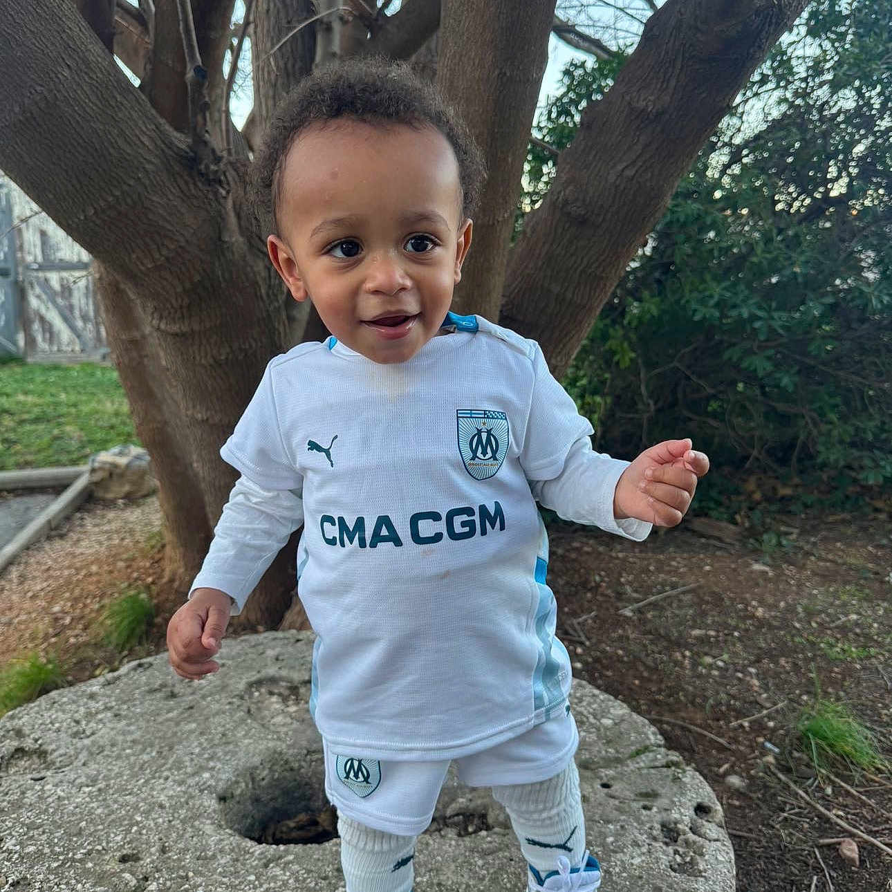 Altaïr participe au concours pour gagner de l'argent avec cette photo : bodypart, boy, child, clothing, face, finger, hand, happy, head, male, pants, person, photography, plant, portrait, rock, sitting, sleeve, standing, tree