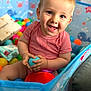 Adam participe au concours pour gagner de l'argent avec cette photo : baby, toddler, child, smiling, happy, ball_pit, toy, indoor, playtime, colorful, red_shirt, blue_ball, cute, portrait, sitting, childrens_toy, face, hand, young_child, play
