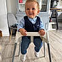 toddler, child, high_chair, blue_shirt, vest, jeans, white_shoes, smile, indoor, kitchen, cabinet, glassware, wood_floor, chair, furniture, person, happy, portrait, casual, modern