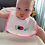 baby, bib, high_chair, food_stain, messy, indoor, curious_eyes, pink_border, ladybug, embroidery, child, infant, face, arm, feeding, cute, young, portrait, messy_face, furniture