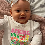 Aurora is registered to the contest to win money with this photo: baby, blanket, bow, child, colorful_clothing, cute, flower_print, gray, hand, happy, headband, infant, lying_down, pink, portrait, smile, soft_texture, spring, toddler, white_shirt