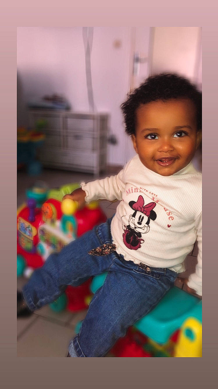 Lya participe au concours pour gagner de l'argent avec cette photo : baby_playing_with_toys, baby_toddler_clothing, cheek, child, facial_expression, flooring, fun, happy, iris, jeans, joy, leg, leisure, person, play, room, sitting, sleeve, smile, t_shirt