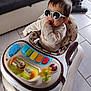 baby, walker, sunglasses, toy, colorful, indoor, floor, tile, child, person, smile, clothing, face, hand, hair, seat, vacuum_cleaner, living_room, furniture, play