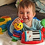 baby, child, smiling, toy, colorful, activity_center, indoor, happy, face, playful, clothing, furniture, blanket, person, infant, cute, young_child, development, joy, home