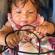 Ariyah is registered to the contest to win money with this photo: baby, blanket, bottle, child, closeup, cord, curly_hair, cute, expression, face, hand, holding, indoors, infant, person, pink_clothing, resting, sitting, skin, young_child