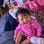 Ariyah is registered to the contest to win money with this photo: baby, pink_clothing, smiling, blanket, bottle, curly_hair, infant, sitting, indoors, soft_texture, cozy, child, cute, happy, person, bed, candid, casual, home, furniture