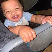 Terrell Jr is registered to the contest to win money with this photo: toddler, child, smile, happy, hand, playpen, baby, face, portrait, indoor, grip, clothing, curly_hair, earrings, skin, toy, mesh, floor, person, closeup