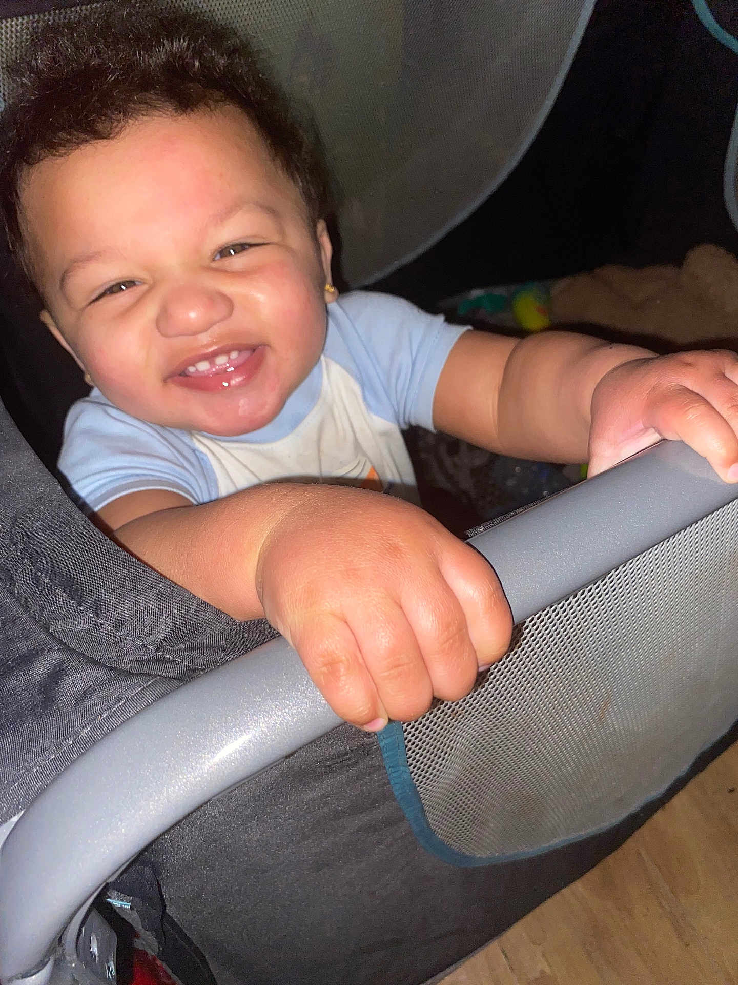 Terrell Jr is registered to the contest to win money with this photo: toddler, child, smile, happy, hand, playpen, baby, face, portrait, indoor, grip, clothing, curly_hair, earrings, skin, toy, mesh, floor, person, closeup
