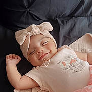 Leilani joined the competition — help win amazing prizes! baby, smiling, headband, bow, blanket, lying_down, cute, infant, soft_texture, happy, child, portrait, clothing, pink, sleepy, peaceful, cozy, face, resting, indoors
