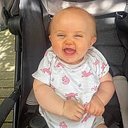 Liya a rejoint le concours — aidez-le/la à gagner de superbes lots ! baby, cheerful, child, clothing, cute, face, hands, happy, infant, onesie, outdoor, person, pink, portrait, seatbelt, sitting, smiling, stroller, sunlight, white