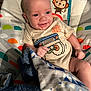 baby, infant, smiling, baby_seat, blanket, clothing, cute, monkey_pattern, colorful, happy, child, indoor, portrait, young_child, toddler, fabric, seat, comfort, playful, wrapped
