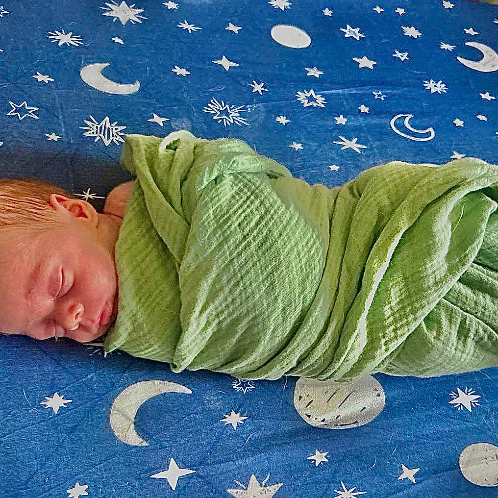 Matthew joined the competition — help win amazing prizes! newborn, baby, sleeping, wrapped, blanket, green_blanket, blue_sheet, stars, moons, planets, cosmic, nursery, infant, peaceful, cute, child, portrait, resting, soft_texture, indoors