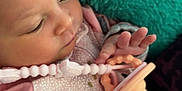 Nova is registered to the contest to win money with this photo: baby, pacifier, pajamas, pink, gray, hand, face, infant, blanket, soft_texture, clothing, sleepwear, newborn, child, person, indoor, closeup, cute, resting, peaceful
