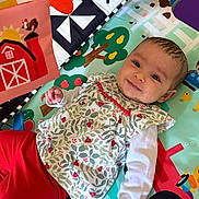 Myla a rejoint le concours — aidez-le/la à gagner de superbes lots ! baby, child, playmat, toy, colorful, smiling, face, red_pants, patterned_clothing, indoor, farm_theme, barn, leafy_pattern, cute, infant, happy, lying_down, playful, hand, eyes