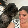 woman, dog, black_dog, selfie, portrait, indoors, bedroom, long_hair, shaggy_fur, chain_collar, striped_shirt, brown_eyes, face, shoulders, candid, pet, companion, dartboard, bed, photography