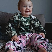 Maisie-May joined the competition — help win amazing prizes! baby, blanket, camo_jacket, child, clothing, couch, cute, face, feet, happy, home, indoor, person, pink_pants, portrait, sitting, smile, toddler, young_child, zigzag_pattern