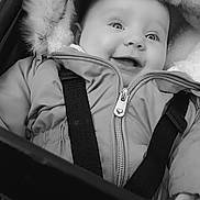 Maisie-May is registered to the contest to win money with this photo: baby, child, smiling, jacket, winter_clothing, fur_hood, stroller, seatbelt, black_and_white, portrait, happy, face, eyes, infant, cute, outdoor, warm_clothing, young_child, expression, close_up