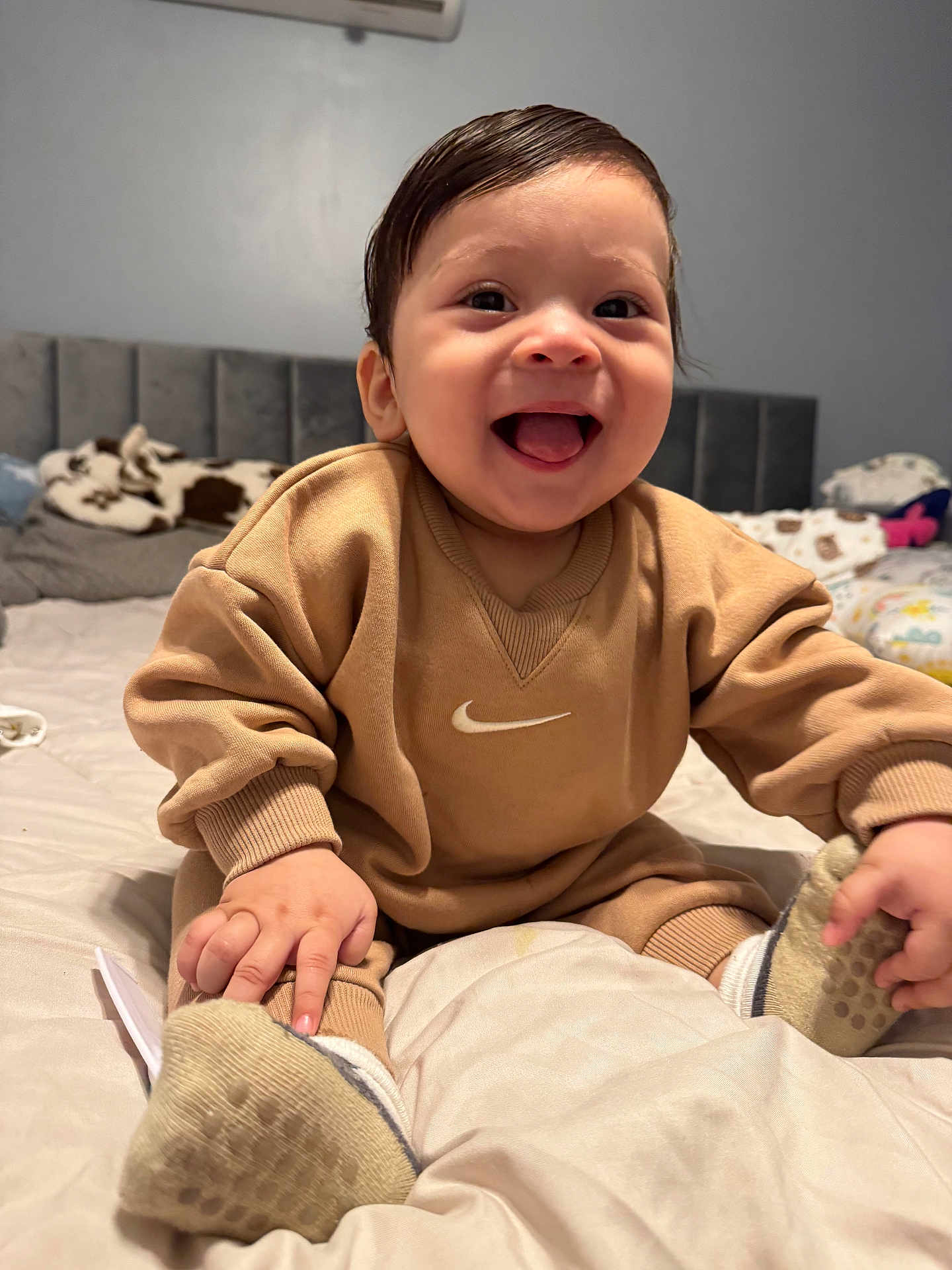 Aarón is registered to the contest to win money with this photo: baby, smiling, infant, bed, clothing, socks, happy, indoors, person, sitting, child, cute, face, young, apparel, footwear, home, joy, portrait, cozy