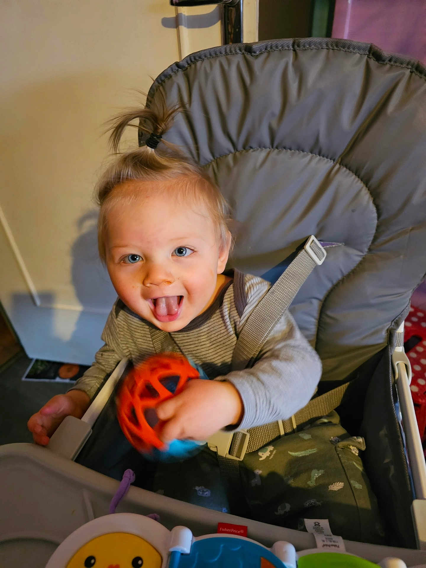 Jonas a rejoint le concours — aidez-le/la à gagner de superbes lots ! toddler, child, high_chair, toy, playful, indoor, happy, smiling, person, clothing, seat_belt, baby, furniture, face, hand, hair, blue_eyes, expression, table, plastic_toy