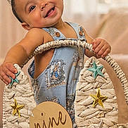 Aaron is registered to the contest to win money with this photo: baby, smiling, infant, basket, stars, blue_outfit, milestone, nine_months, cute, happy, child, portrait, indoor, decor, celebration, hand, face, young_child, clothing, person