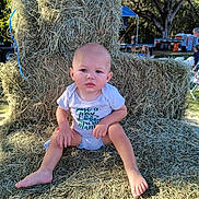 Walker is registered to the contest to win money with this photo: baby, child, hay, outdoor, nature, grass, seat, throne, person, trees, sunlight, people, summer, casual, barefoot, expression, sitting, daytime, blue_sky, event
