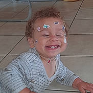 Saïan a rejoint le concours — aidez-le/la à gagner de superbes lots ! toddler, child, smiling, stickers, face, crawling, floor, tile, happy, indoor, clothing, long_sleeve, curly_hair, baby, playful, cute, person, home, toy, joyful