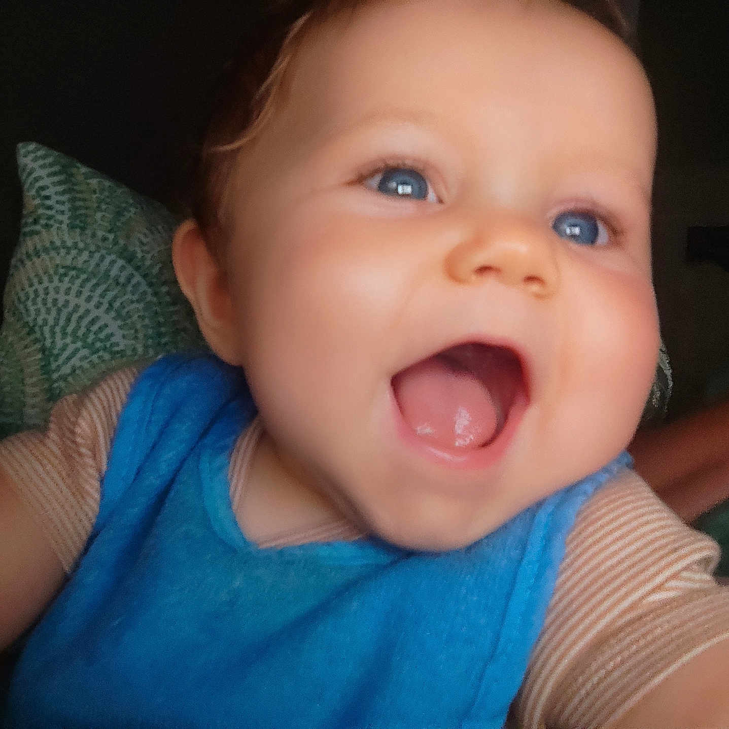 Jules a rejoint le concours — aidez-le/la à gagner de superbes lots ! baby, bib, blue_eyes, child, close_up, cute, expression, face, happy, indoor, infant, joyful, mouth_open, pattern, person, pillow, skin, smile, soft_lighting, striped_shirt