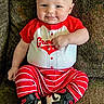 baby, casual, child, couch, cute, face, footwear, happy, head, indoor, infant, nike, person, portrait, red_clothing, sitting, smiling, sneakers, striped_pants, young