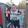 Raphaël a rejoint le concours — aidez-le/la à gagner de superbes lots ! toddler, child, playground, smiling, happy, outdoor, play, person, clothing, jacket, pants, shoes, metal_bar, wooden_poles, fun, daylight, trees, autumn, park, recreation
