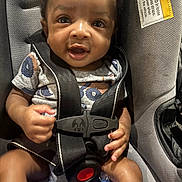 Liam is registered to the contest to win money with this photo: baby, car_seat, child, infant, harness, pacifier, toy, clothing, face, hands, seatbelt, safety, person, closeup, expression, cute, indoor, warning_label, smiling, portrait