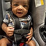 baby, car_seat, child, infant, harness, pacifier, toy, clothing, face, hands, seatbelt, safety, person, closeup, expression, cute, indoor, warning_label, smiling, portrait