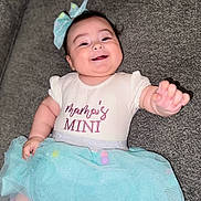 Ebony is registered to the contest to win money with this photo: baby, bow, celebration, child, clothing, couch, cute, cute_expression, dress, fabric, fun, happy, indoor, infant, person, portrait, sitting, smiling, soft, tutu