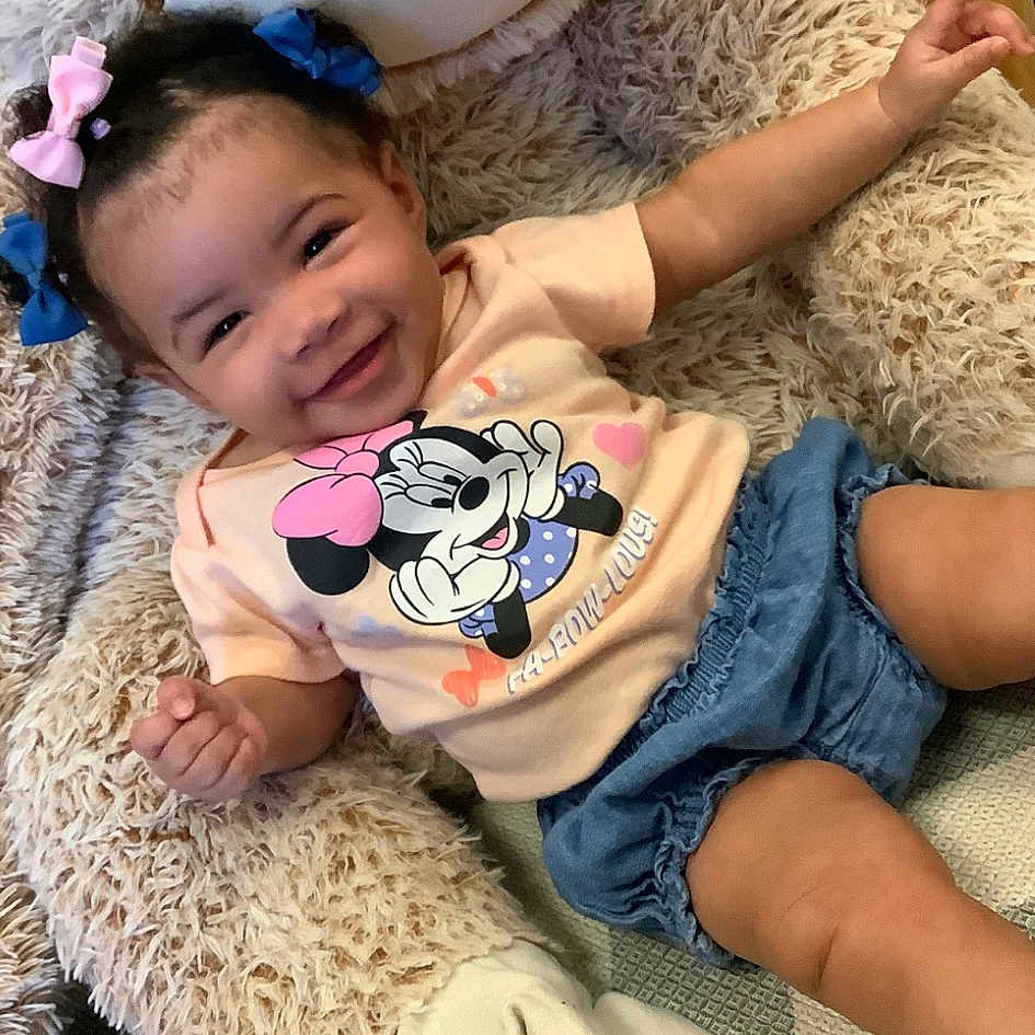 Christine joined the competition — help win amazing prizes! toddler, child, smiling, hair_bows, minnie_mouse, tshirt, denim_shorts, stuffed_animal, fluffy, cute, happy, indoors, playful, baby, person, portrait, sitting, clothing, joyful, relaxed