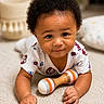Kaizen is registered to the contest to win money with this photo: baby, infant, child, curly_hair, rattle, toy, carpet, crawling, indoor, cute, smiling, clothing, short_sleeve, person, face, hand, home, cozy, soft, background