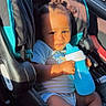 toddler, child, car_seat, sippy_cup, curly_hair, sunlight, shadow, baby_clothes, car_interior, seat_belt, infant, cute, young_child, person, portrait, sitting, holding, daylight, car_door, window
