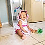 Nélia participe au concours pour gagner de l'argent avec cette photo : baby, cabinet, child, curious, door, dress, floor, foot, green_chair, happy, hat, indoor, kitchen, person, plastic_bottle, sitting, smile, tile, toddler, washing_machine