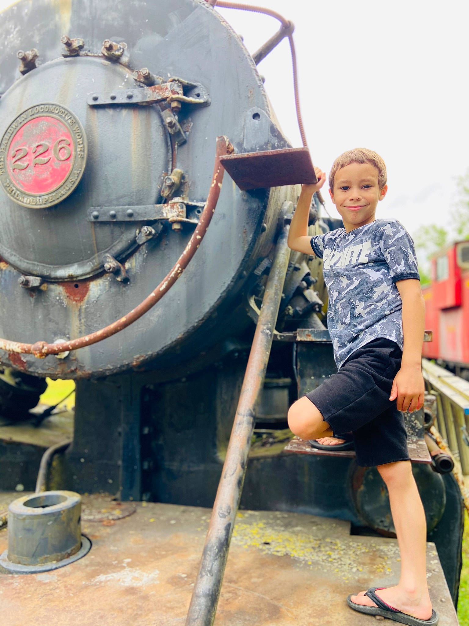 Denver is registered to the contest to win money with this photo: auto_part, engineering, flip_flops, fun, gas, joy, leisure, machine, naval_architecture, person, sandal, shorts, sky, smile, t_shirt, toddler