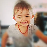Maë a rejoint le concours — aidez-le/la à gagner de superbes lots ! toddler, child, smiling, face, necklace, amber, short_hair, indoors, blurred_background, happy, person, cute, casual_clothing, portrait, young_child, baby, head, skin, expression, warm_lighting