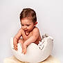 Maë participe au concours pour gagner de l'argent avec cette photo : baby, child, infant, eggshell, prop, necklace, curious, cute, soft, white, fluff, rug, studio, portrait, hands, exploring, sitting, naked, skin, indoors