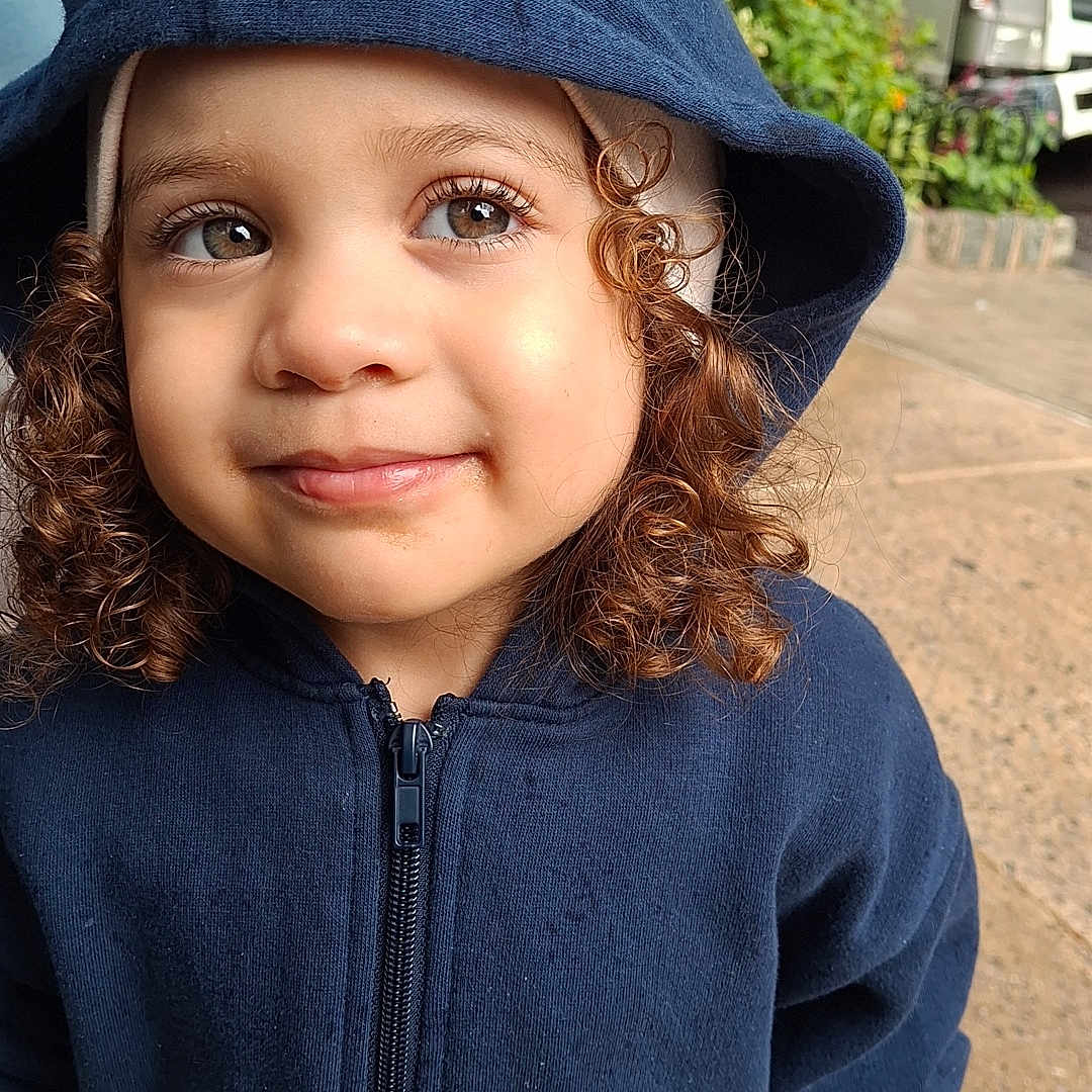 Reychell joined the competition — help win amazing prizes! casual_clothing, child, curly_hair, cute, daylight, face, flower, greenery, hooded_jacket, looking_away, navy_blue, outdoor, person, portrait, sidewalk, smiling, toddler, truck, young_child, zipper
