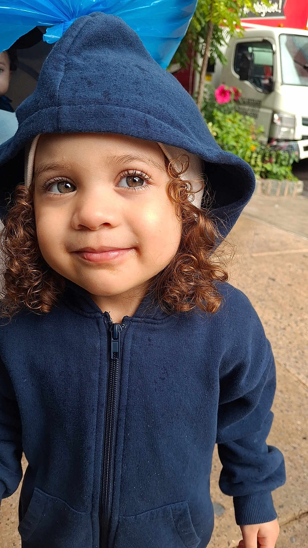 Reychell joined the competition — help win amazing prizes! casual_clothing, child, curly_hair, cute, daylight, face, flower, greenery, hooded_jacket, looking_away, navy_blue, outdoor, person, portrait, sidewalk, smiling, toddler, truck, young_child, zipper