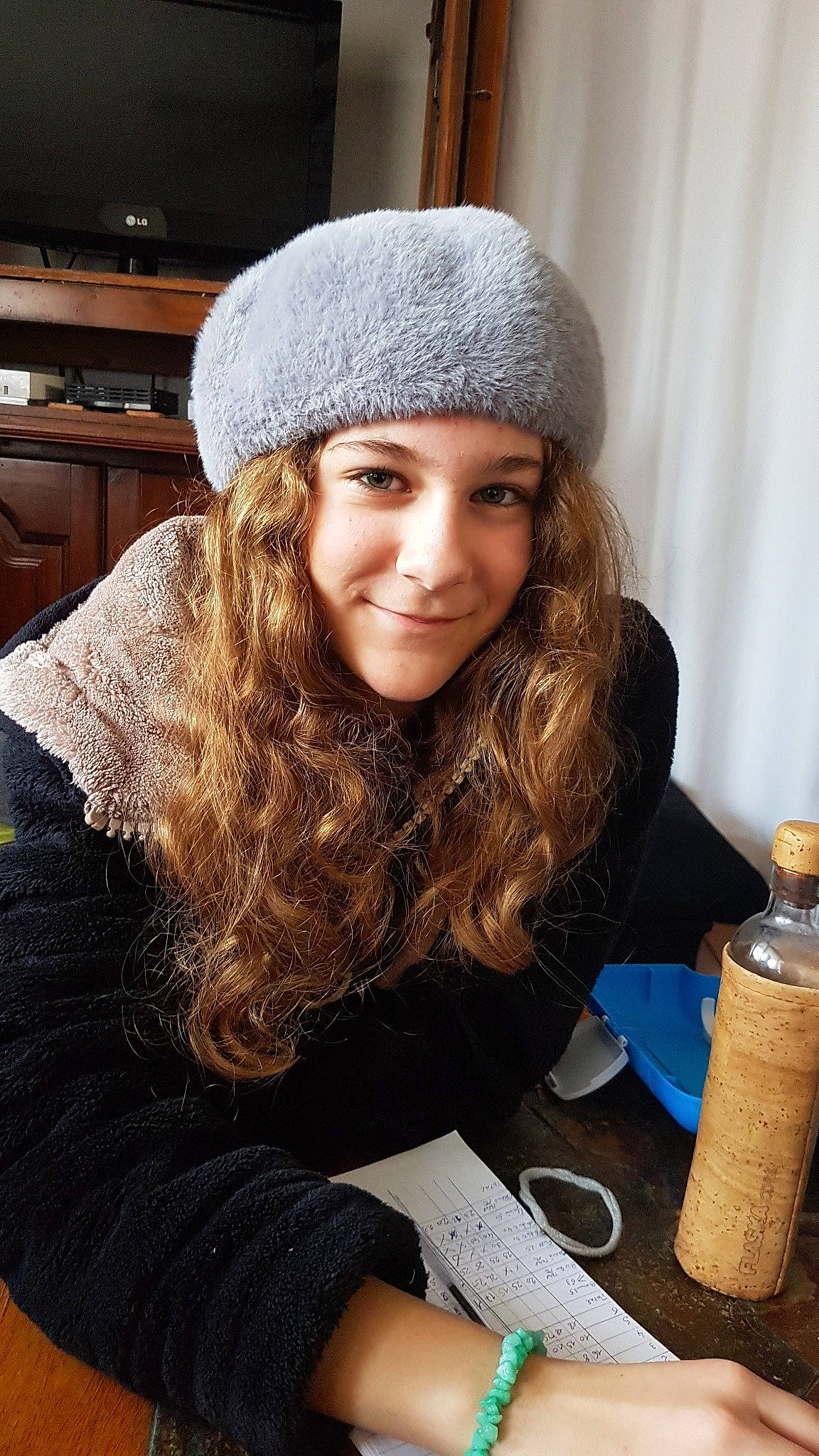 Lya participe au concours pour gagner de l'argent avec cette photo : arm, beauty, black_hair, brown_hair, cap, curtain, fashion_accessory, fashion_design, fun, fur, happy, headgear, headwear, joy, knit_cap, long_hair, person, sitting, smile, tree