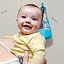 Eli joined the competition — help win amazing prizes! baby, smiling, yellow_clothing, striped, infant, hand, tattoo, wall, bib, blue, happy, person, face, portrait, holding, indoor, cute, child, skin, apparel