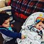 Eli is registered to the contest to win money with this photo: toddler, baby, indoor, blanket, baby_seat, pillow, child, curly_hair, couch, plaid_blanket, soft_toys, cozy, infant, young_child, clothing, home, family, cute, comfort, interaction