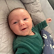 Ezio participe au concours pour gagner de l'argent avec cette photo : baby, smiling, infant, green_clothing, blanket, blue_blanket, moon_pattern, star_pattern, quilted_cushion, lying_down, face, head, happy, indoors, cozy, child, person, cute, newborn, comfort