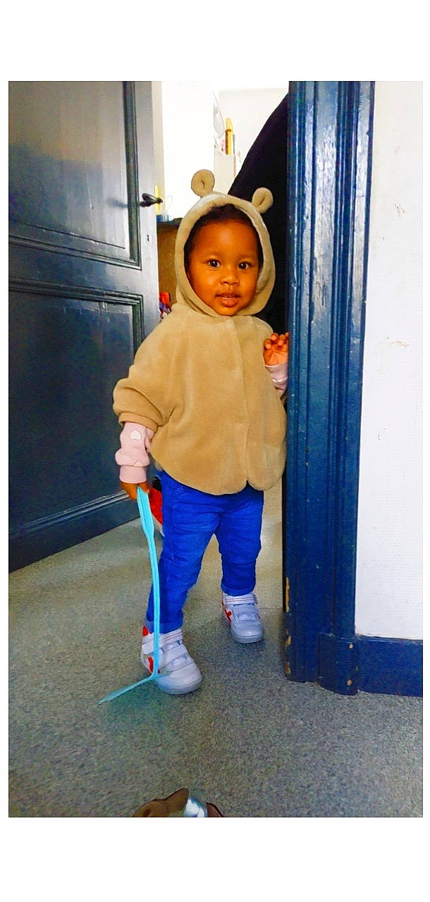 Maimouna Didi participe au concours pour gagner de l'argent avec cette photo : baby, baby_toddler_clothing, child, denim, door, electric_blue, flooring, footwear, gesture, happy, human_leg, knee, person, room, sleeve, smile, standing, sweatpant, thumb, toddler