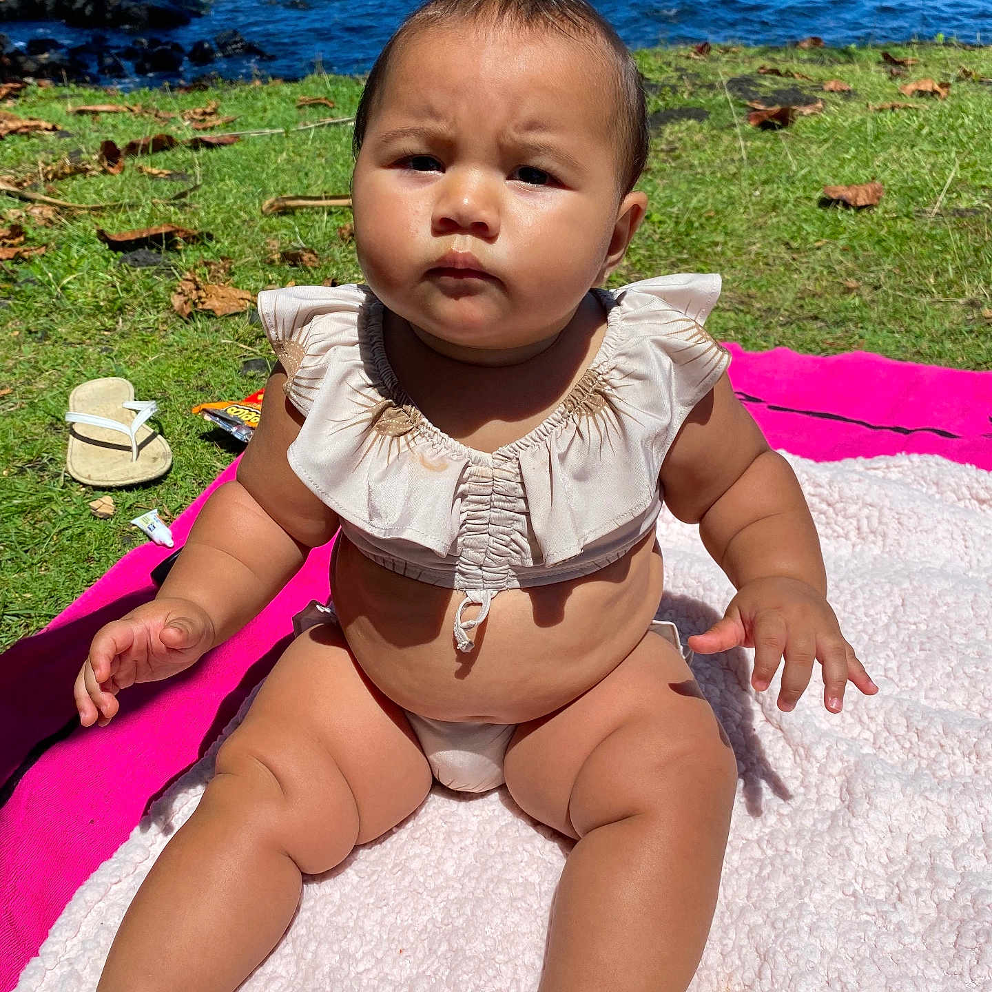 Kalohelani is registered to the contest to win money with this photo: baby, beach, clothing, coast, face, grass, head, nature, outdoors, person, photography, plant, portrait, rock, sea, shoreline, sitting, summer, swimwear, water