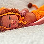 Oakley joined the competition — help win amazing prizes! baby, newborn, infant, lying_down, knitted_clothing, lion_costume, orange, fluffy_surface, soft_texture, cute, portrait, face, headwear, animal_costume, cozy, small_hands, baby_gaze, warm_colors, indoors, sleepy